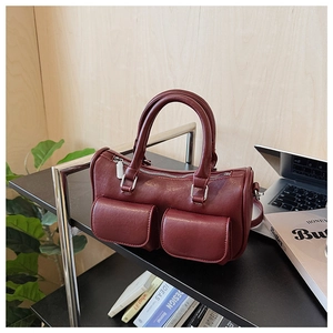 Detail of burgundy leather mini bag with dual front flap pockets and silver metal hardware