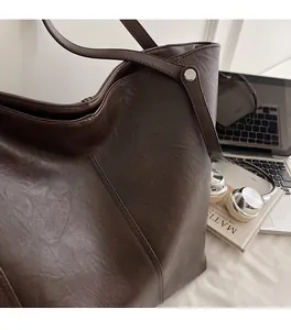 Dettaglio della borsa tote marrone scuro con trama in pelle pregiata e cuciture rifinite