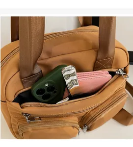 Detail of nylon crossbody bag with multiple zip pockets showing storage for phone and wallet