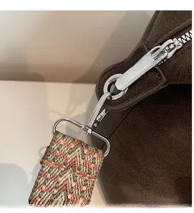 Close-up of brown suede pillow bag with silver metal hardware and ethnic patterned strap