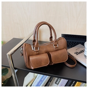 Detail of a brown matte leather Boston bag with symmetrical front flap pockets and straps