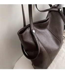 Dettaglio della borsa tote marrone scuro con trama in pelle vintage e rivetti argentati