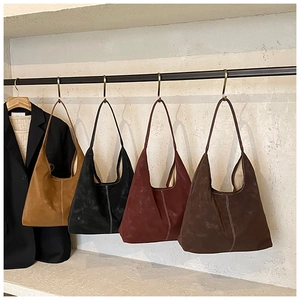 Detail of four suede hobo bags in autumn colors with vertical white stitching detail