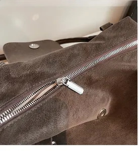 Macro shot of the smooth silver zipper detail on a dark brown suede pillow handbag