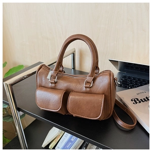 Brown leather Boston bag with dual front pockets and adjustable shoulder strap detail