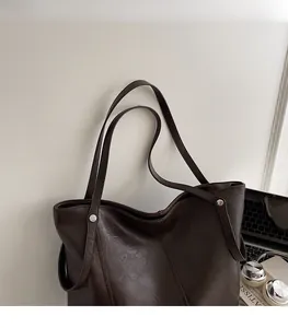 Dettaglio della grande borsa tote in pelle marrone scuro con rivetti e doppi spallacci