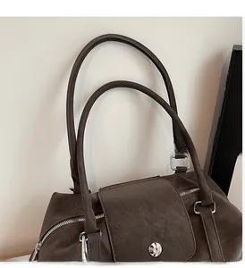 Close-up of pebble grain leather handbag showing top handles and silver buckle detail