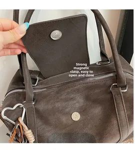 Detail of strong magnetic snap closure on deep brown pebbled leather boston bag