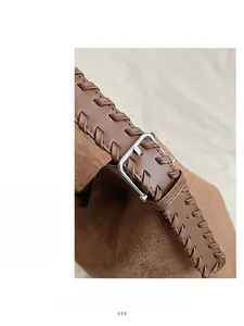 Detail of brown suede tote with woven leather strap and adjustable silver square buckle