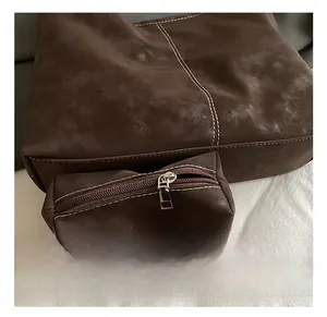 Detail of dark brown matte tote bag set with white contrast stitching and silver zipper