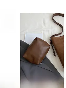 Detail view of brown suede bucket bag with leather inner pouch and woven shoulder strap
