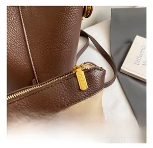 Close-up of premium dark brown lychee leather bag with engraved golden zipper detail