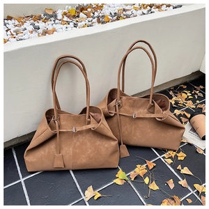 Macro detail of brown oversized tote bag with vintage matte finish and slim shoulder strap