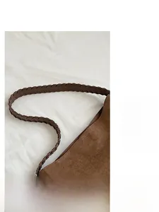 Detail of a brown faux suede tote bag featuring a dark brown braided leather shoulder strap