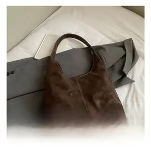 Close-up of brown suede tote bag featuring distinctive white contrast stitching details