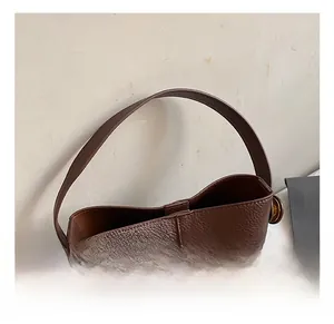 Detail of wide coffee leather top handle and metal buckle on the minimalist bucket bag
