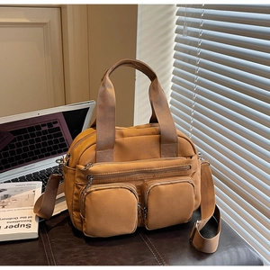 Detail view of mustard yellow multi-pocket nylon crossbody bag with adjustable strap