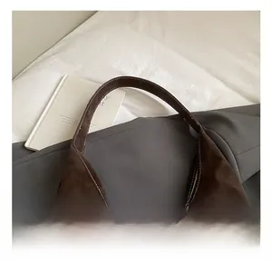 Detail view of large brown suede tote bag with contrast stitching on elegant background