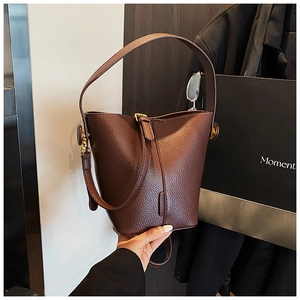 Detail of brown litchi pattern leather bucket bag with gold hardware and strap
