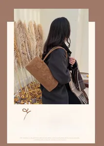 Détail du sac sous le bras en daim marron avec coutures décoratives et longue anse