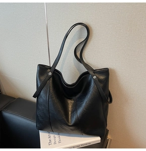 Dettaglio della borsa tote in pelle nera con texture fine e rivetti in metallo