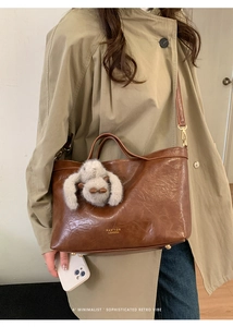 Detail of retro brown leather handbag featuring a plush rabbit pendant and brand logo
