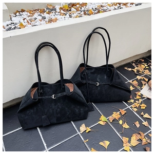 Detail of two large black suede tote bags with metal buckles in an autumn setting