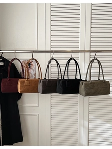 Cinq sacs vintage en bordeaux, marron et vert exposés sur un support métallique