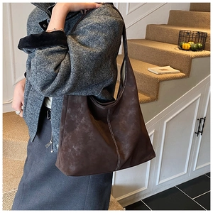 Detail of dark brown tote bag with contrast white stitching and premium matte leather texture