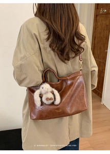 Detail showing the brown vintage leather texture and brand logo with a plush rabbit charm