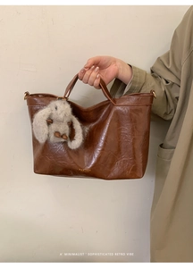 Detail of vintage brown leather tote bag with gold hardware and a cute rabbit charm