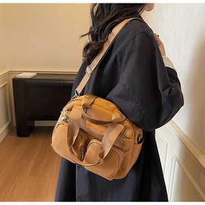 Detailed view of caramel nylon crossbody bag with multiple zippers and adjustable strap