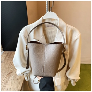 Detail of taupe litchi grain leather bucket bag with top handle and adjustable strap