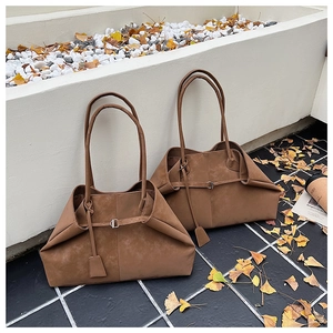 Macro detail of dark brown foldable suede tote bag with stylish buckle and leather tag