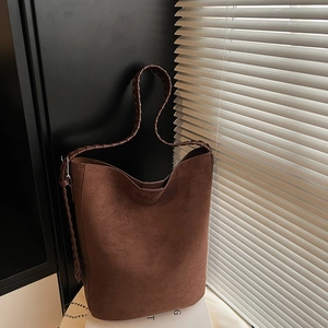 Macro detail of dark brown faux suede tote bag with unique woven shoulder strap design