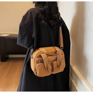 Detailed view of caramel nylon crossbody bag featuring multiple functional zipper pockets
