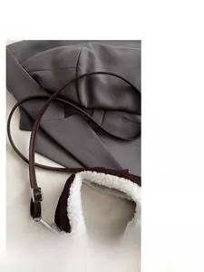 Dettaglio della tracolla in pelle marrone scuro con fibbia argento e fodera in peluche