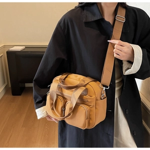 Detail of dark khaki crossbody bag with multi-pocket design and adjustable wide strap