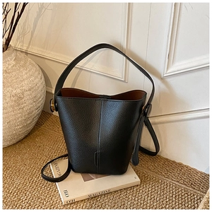 Detail of lychee pattern leather bucket bag with contrast brown lining and gold hardware buckle