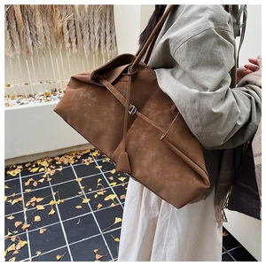 Detail of dark brown tote bag with geometric fold design and silver metal buckle