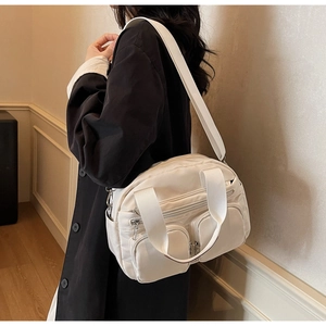 Side view of white multi-pocket nylon crossbody bag worn on shoulder for daily use
