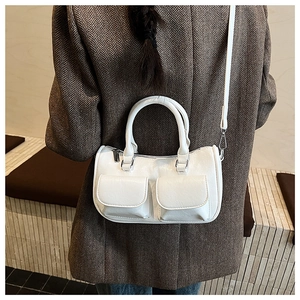 Close-up of a white textured PU leather handbag worn with a brown herringbone coat
