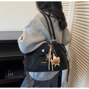 Detail of black matte tote bag with geometric wide strap and cute bear charm pendant