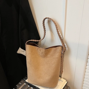Close-up of the stylish braided shoulder strap on a camel faux suede bucket tote bag