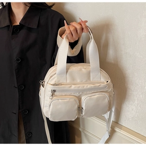 Close-up of beige multi-pocket crossbody bag with high-density nylon texture and wide straps