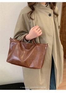 Detail of retro dark brown tote bag with gold lettering and polished leather texture