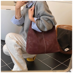 Mirror selfie showing a person wearing a large burgundy suede tote bag with white stitching