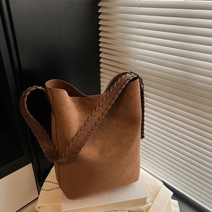 Detailed view of woven handle and suede texture on a brown vintage bucket tote bag