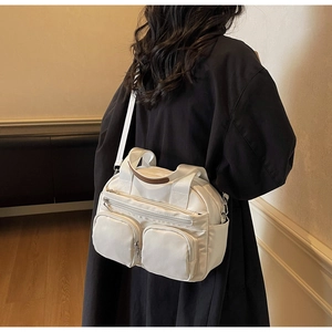 Close-up of white nylon crossbody bag with multi-pocket design and brown leather trim