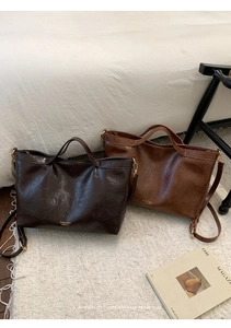 Detail of vintage faux leather tote bags in dark coffee and caramel with metal buckles